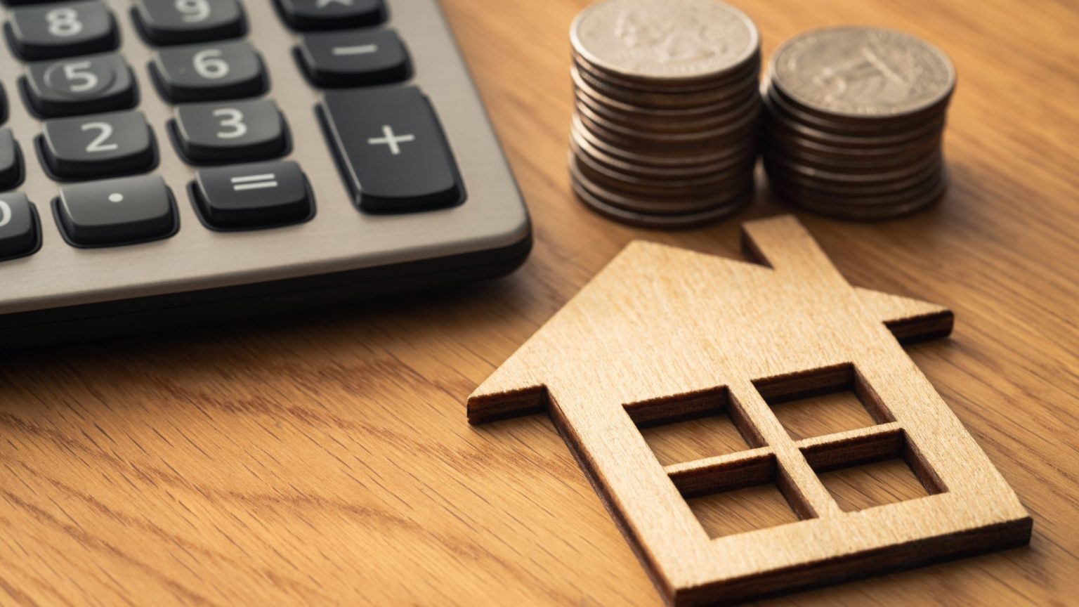 House figurine, coins, calculator on table.