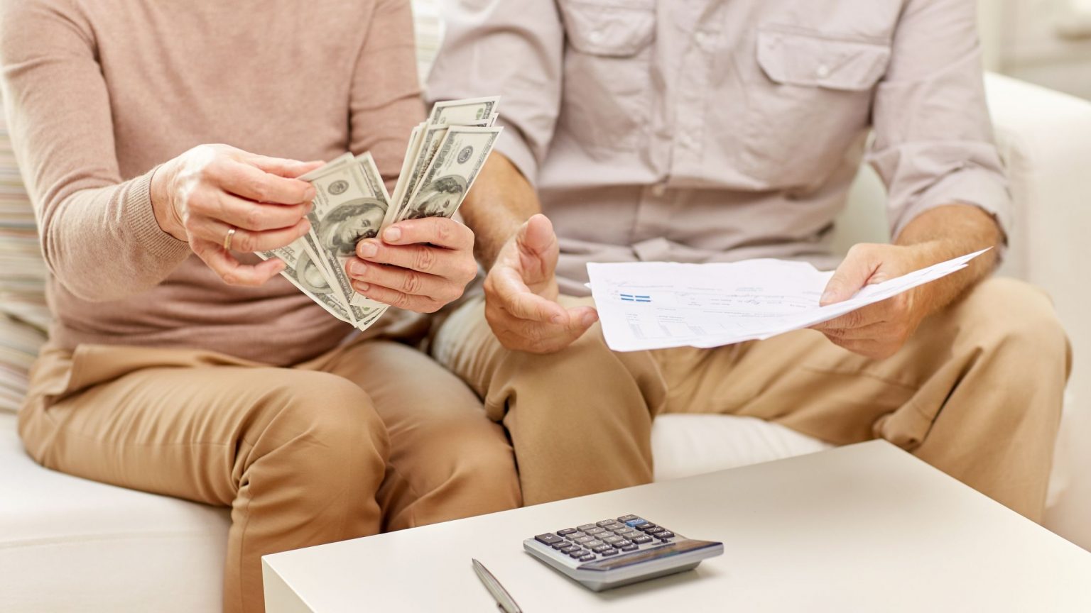 Couple holding money and papers, deciding how to use their home equity line of credit funds.