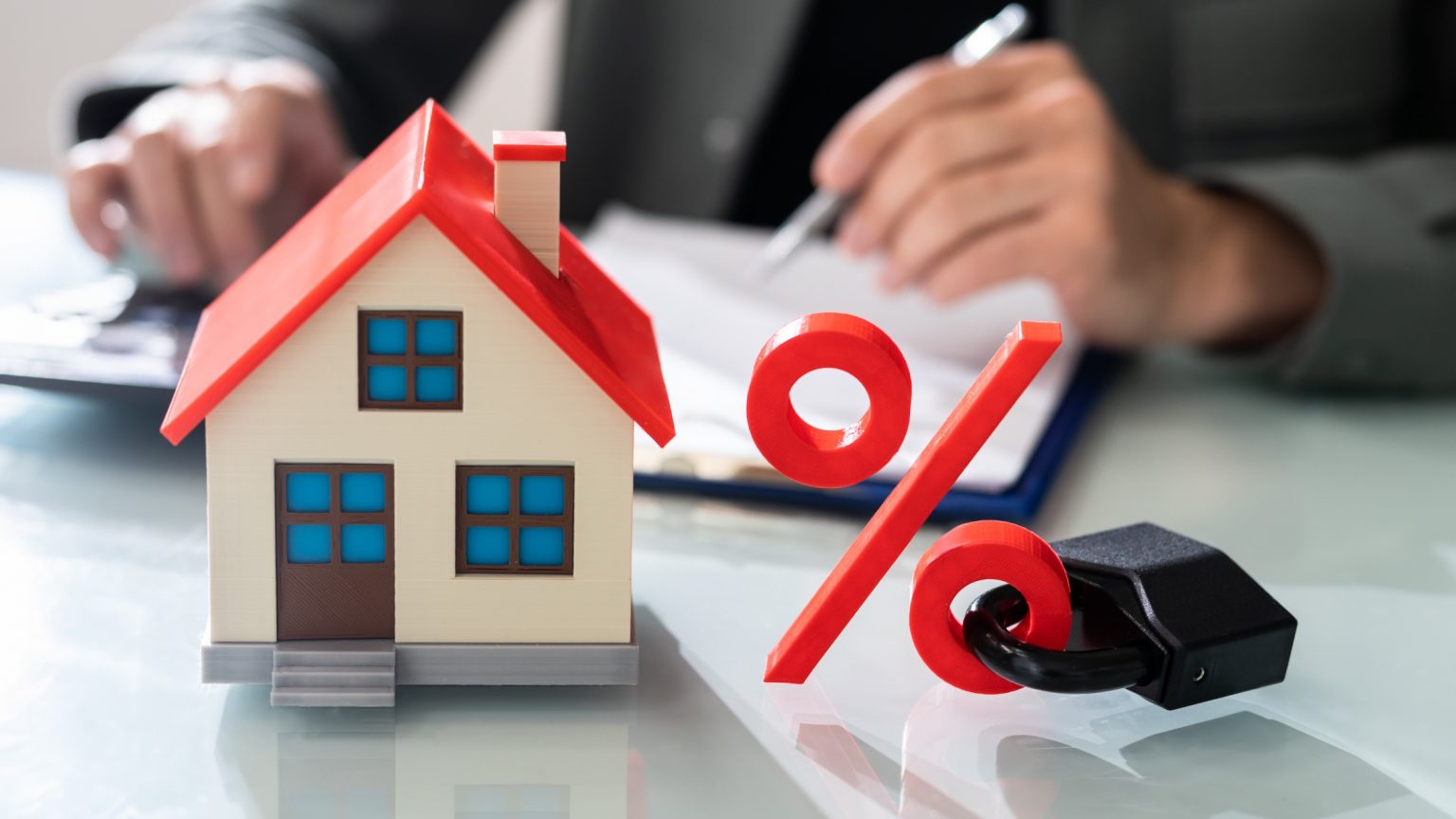 House and interest rate percentage figurines with lock on the percentage symbol.