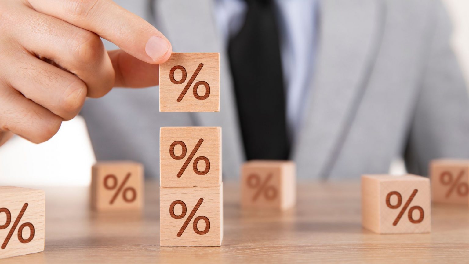 Stacking blocks of percentage symbols, symbolizing rising interest rates.