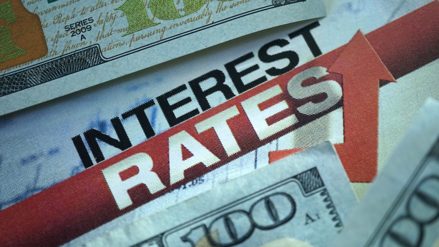 Interest rates rising, red up arrow, $100 dollar bills in the background.