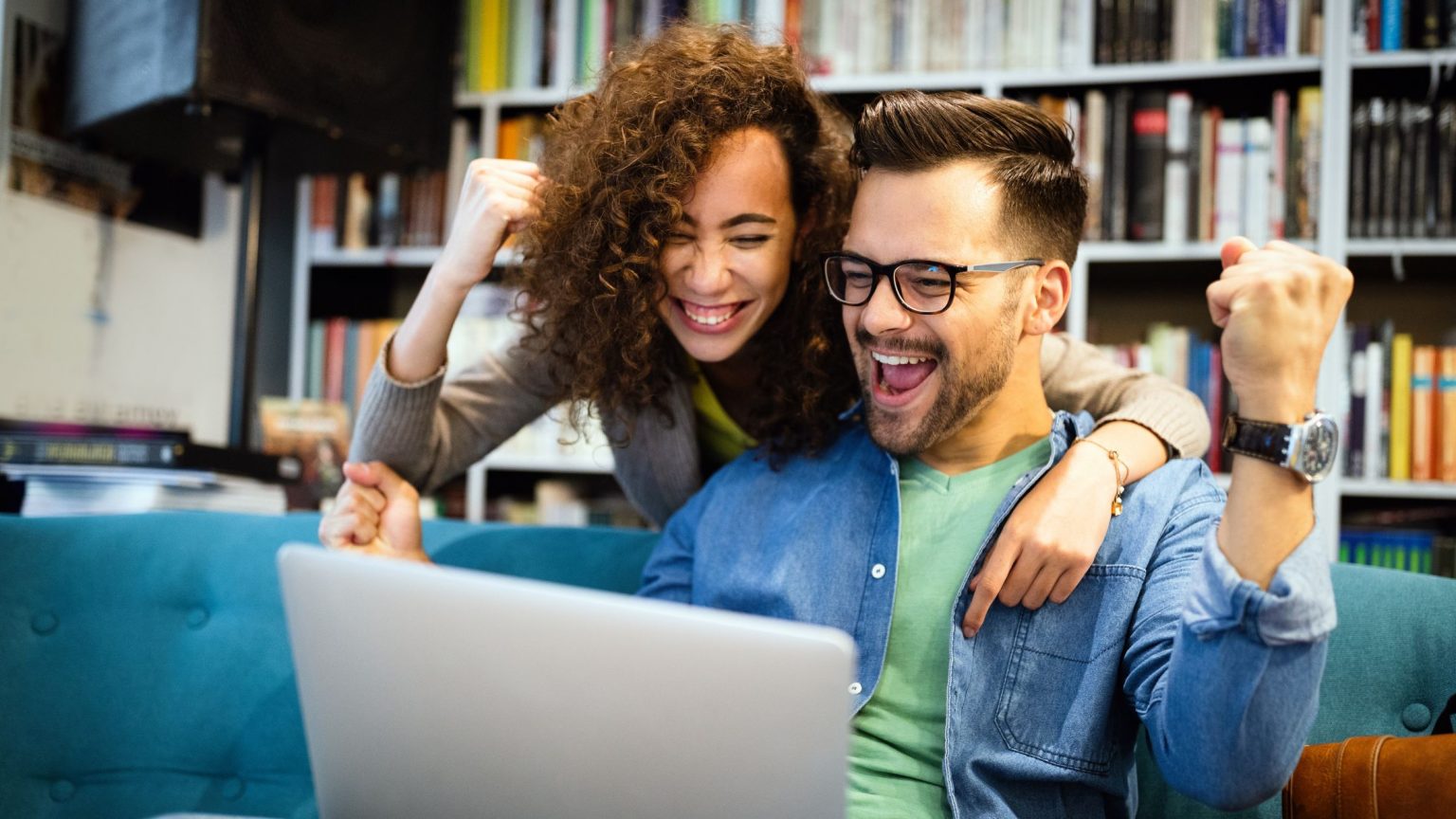 Happy couple excited and smiling at their laptop after getting cleared to close by their online digital remote mortgage lender.