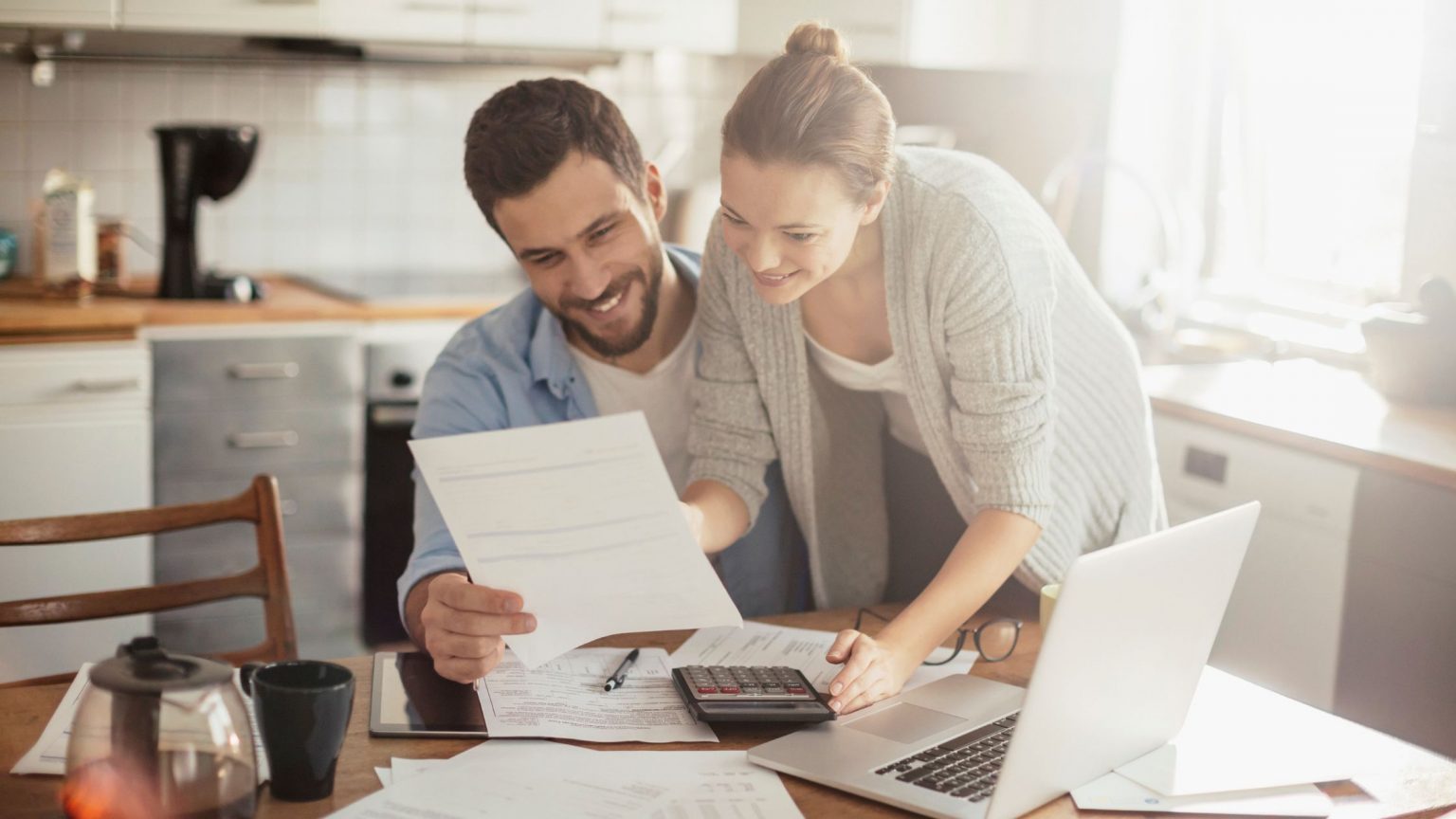 Young happy couple looking at documents and their laptop to budget.