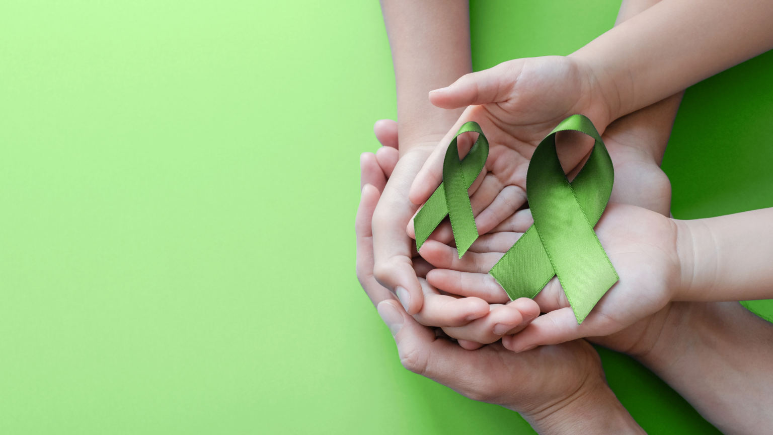 Mother and young daughter holding green ribbons in hand over green background in honor of Mental Health Awareness month.
