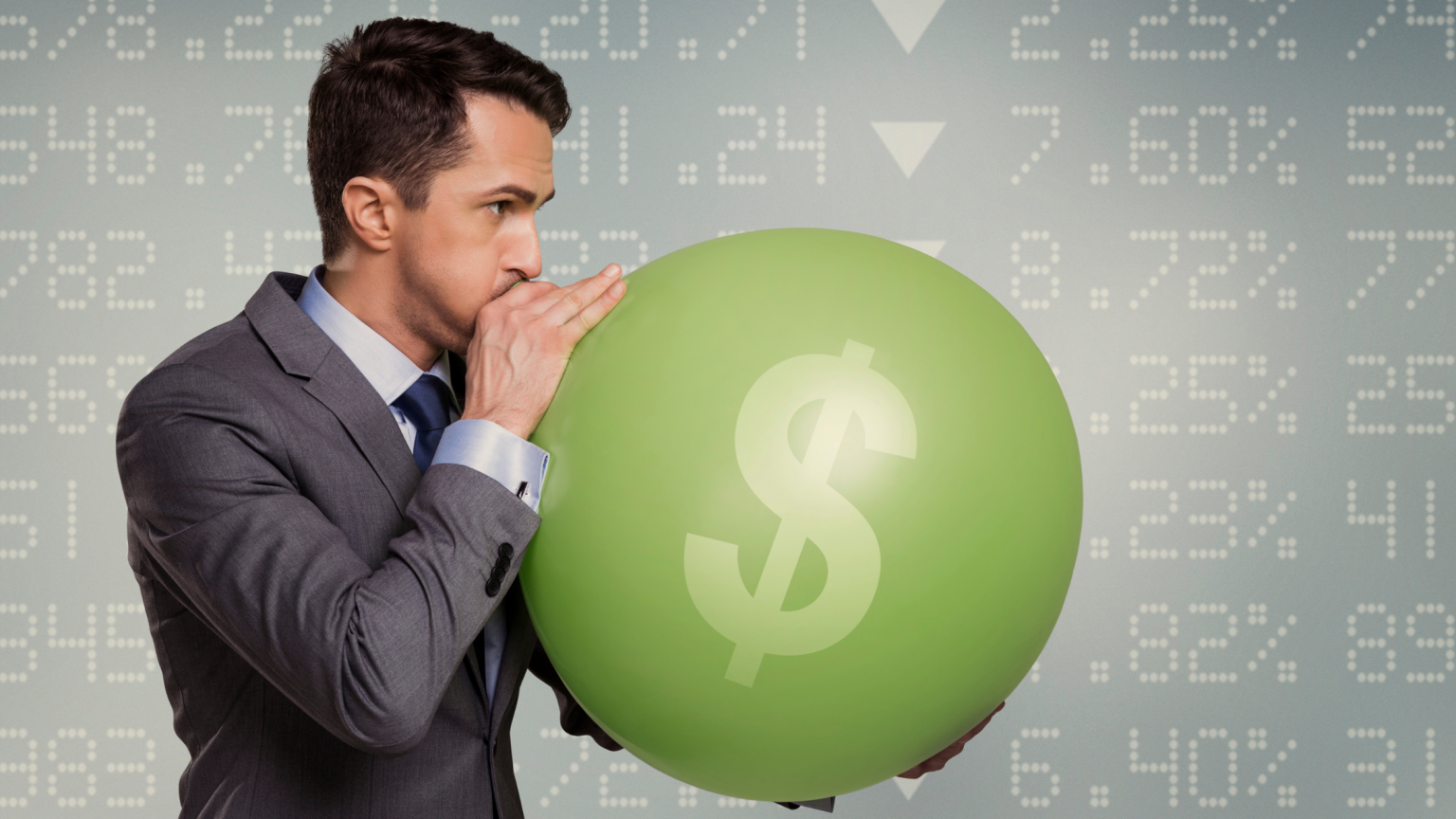 Business man blowing up green ballon with dollar sign symbol on it. Percentages and numbers in the background with down arrows.